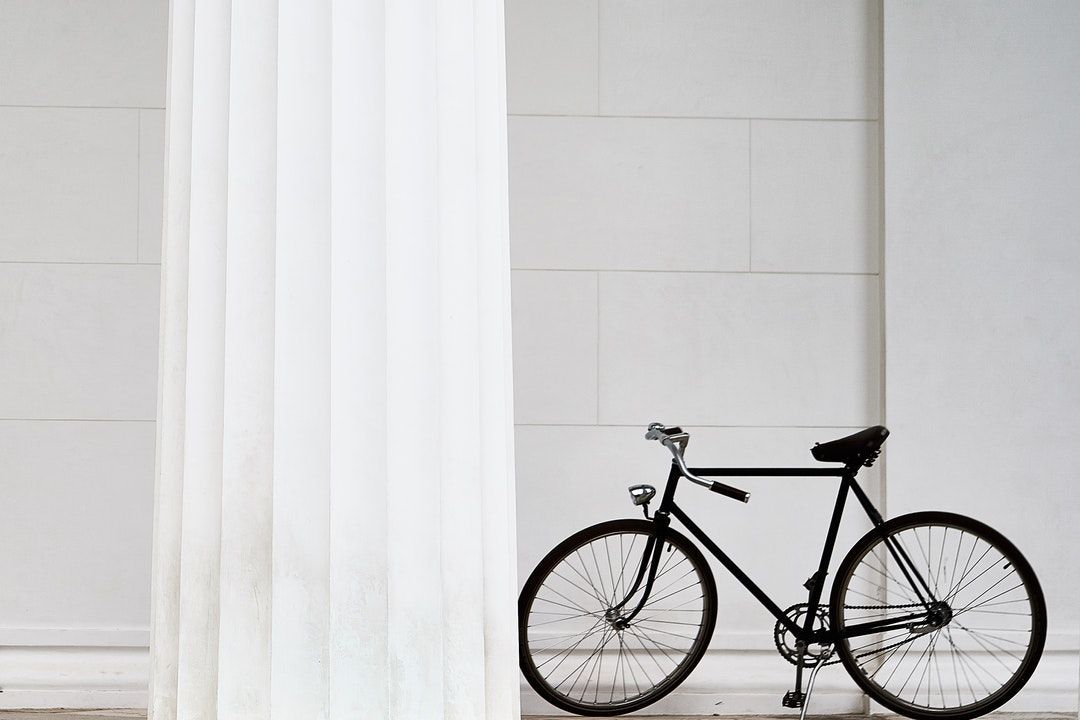 black bicycle standing on white concrete building