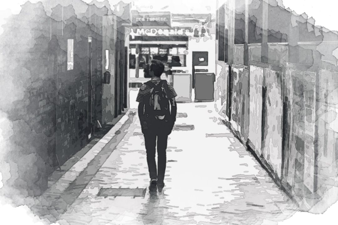 man walking between concrete buildings