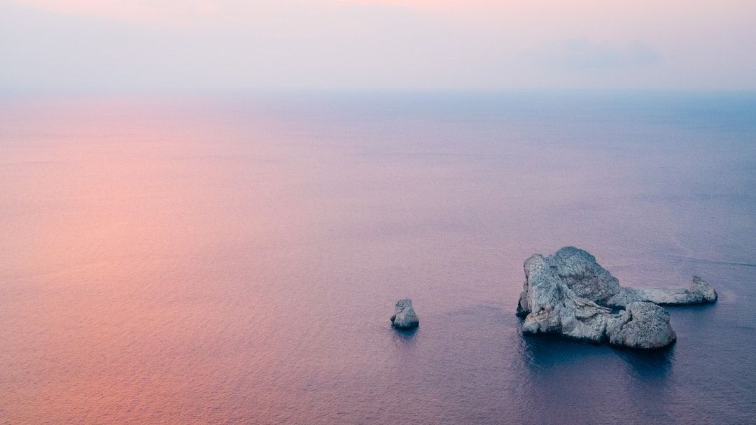 aerial photography of brown rock formation near body of water